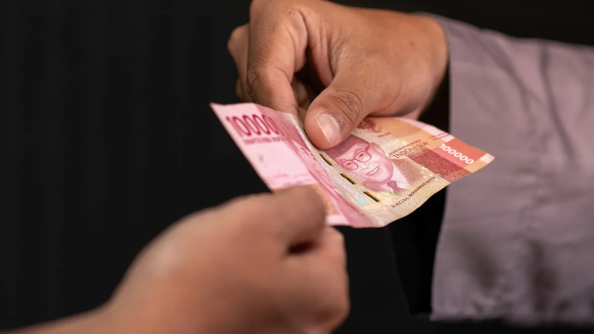 Ilustrasi dua tangan menyerahkan uang rupiah